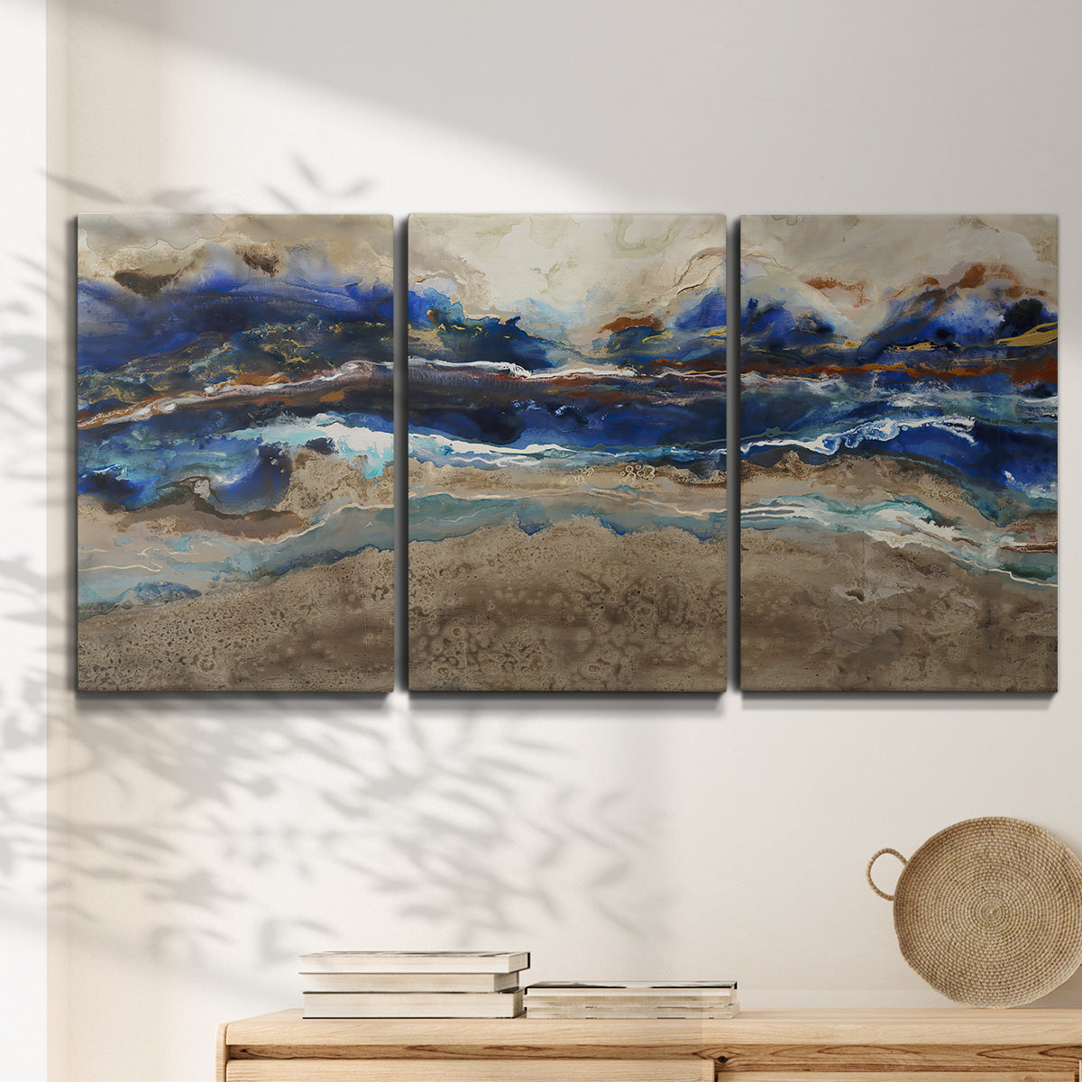 Three-panel canvas wall art featuring abstract coastal jewel toned composition, displayed in a minimalist living room above a console table.