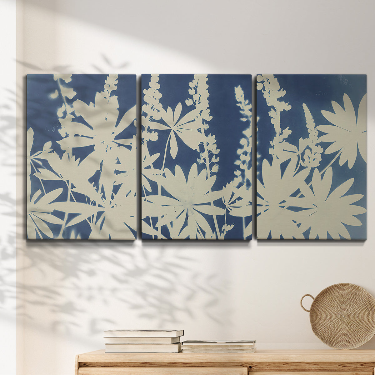 Three-panel canvas wall art featuring delicate lupine floral composition, displayed in a minimalist living room above a console table.