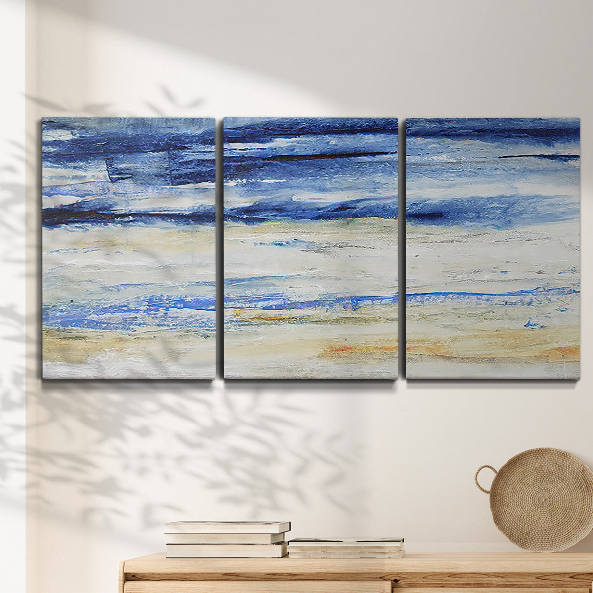 Three-panel canvas wall art featuring turbulent abstract ocean wave motion, displayed in a minimalist living room above a console table.