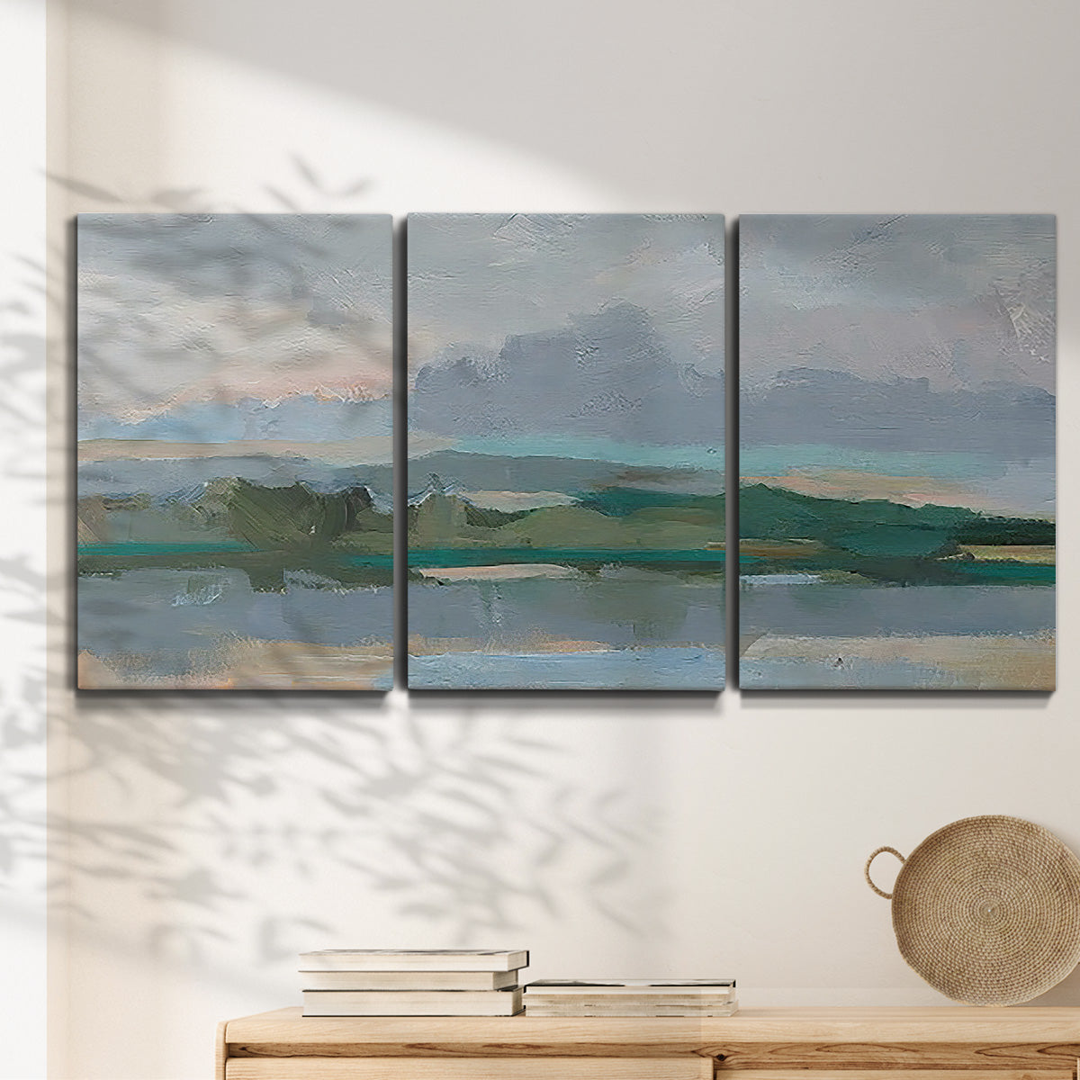 Three-panel canvas wall art featuring twilight landscape with fading light, displayed in a minimalist living room above a console table.