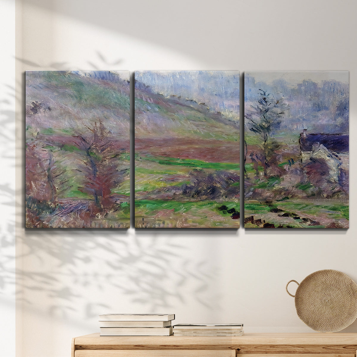 Three-panel canvas wall art featuring cliffside cottage overlooking sea, displayed in a minimalist living room above a console table.