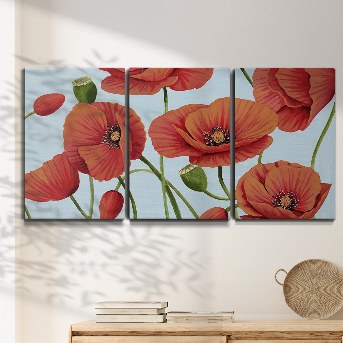 Three-panel canvas wall art featuring red poppies in motion, displayed in a minimalist living room above a console table.