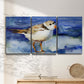 Three-panel canvas wall art featuring shorebirds standing in shallow water, displayed in a minimalist living room above a console table.