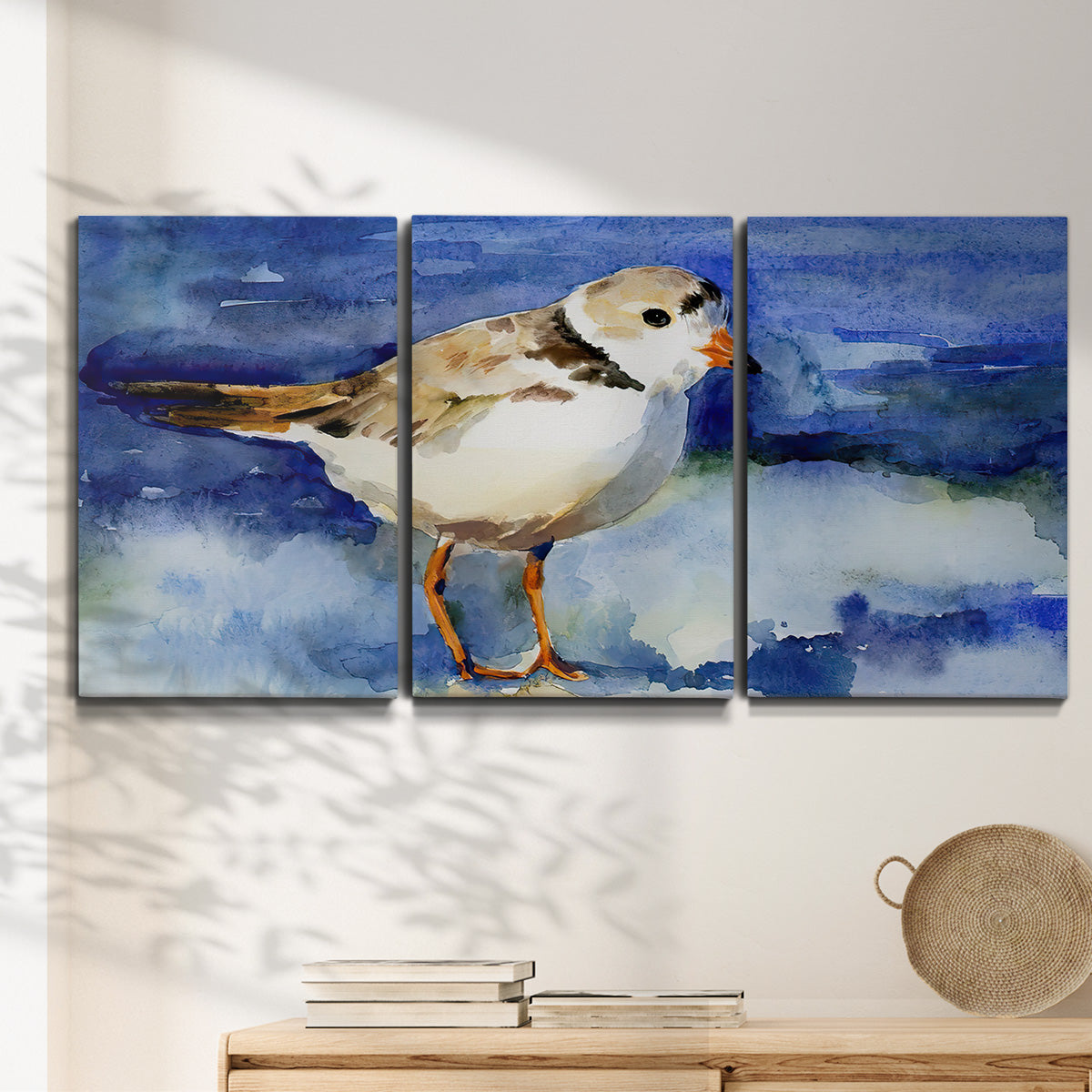 Three-panel canvas wall art featuring shorebirds standing in shallow water, displayed in a minimalist living room above a console table.