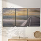 Three-panel canvas wall art featuring tropical beach at sunset photograph, displayed in a minimalist living room above a console table.