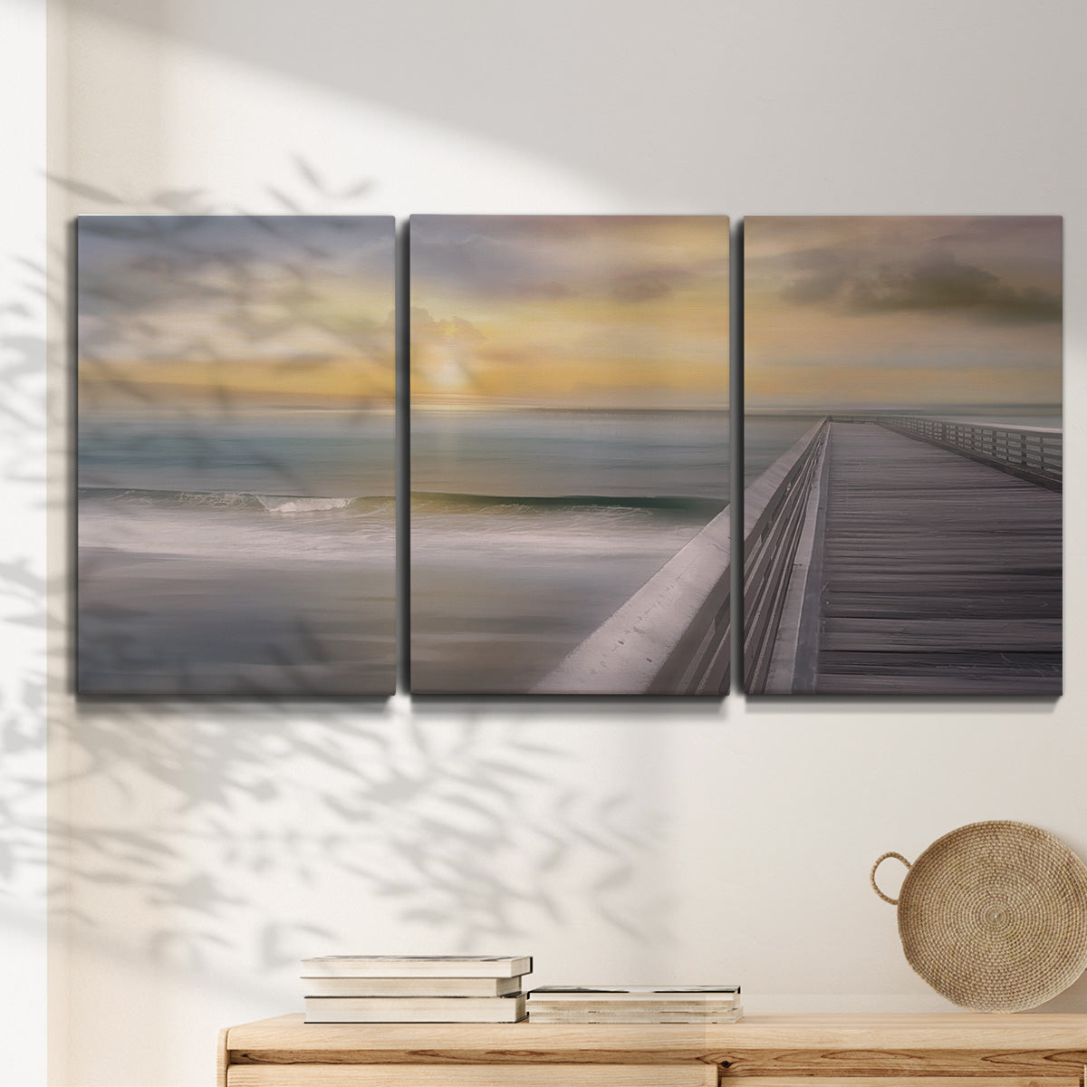 Three-panel canvas wall art featuring tropical beach at sunset photograph, displayed in a minimalist living room above a console table.
