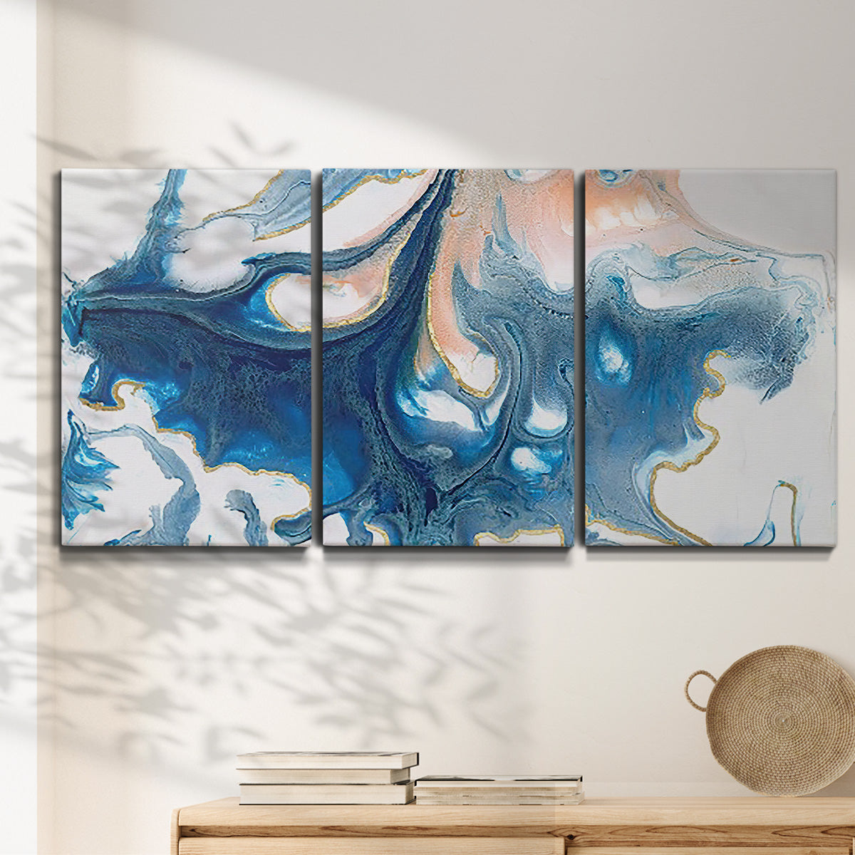 Three-panel canvas wall art featuring flowing blue abstract movement, displayed in a minimalist living room above a console table.