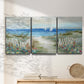 Three-panel canvas wall art featuring lush coastal garden landscape, displayed in a minimalist living room above a console table.