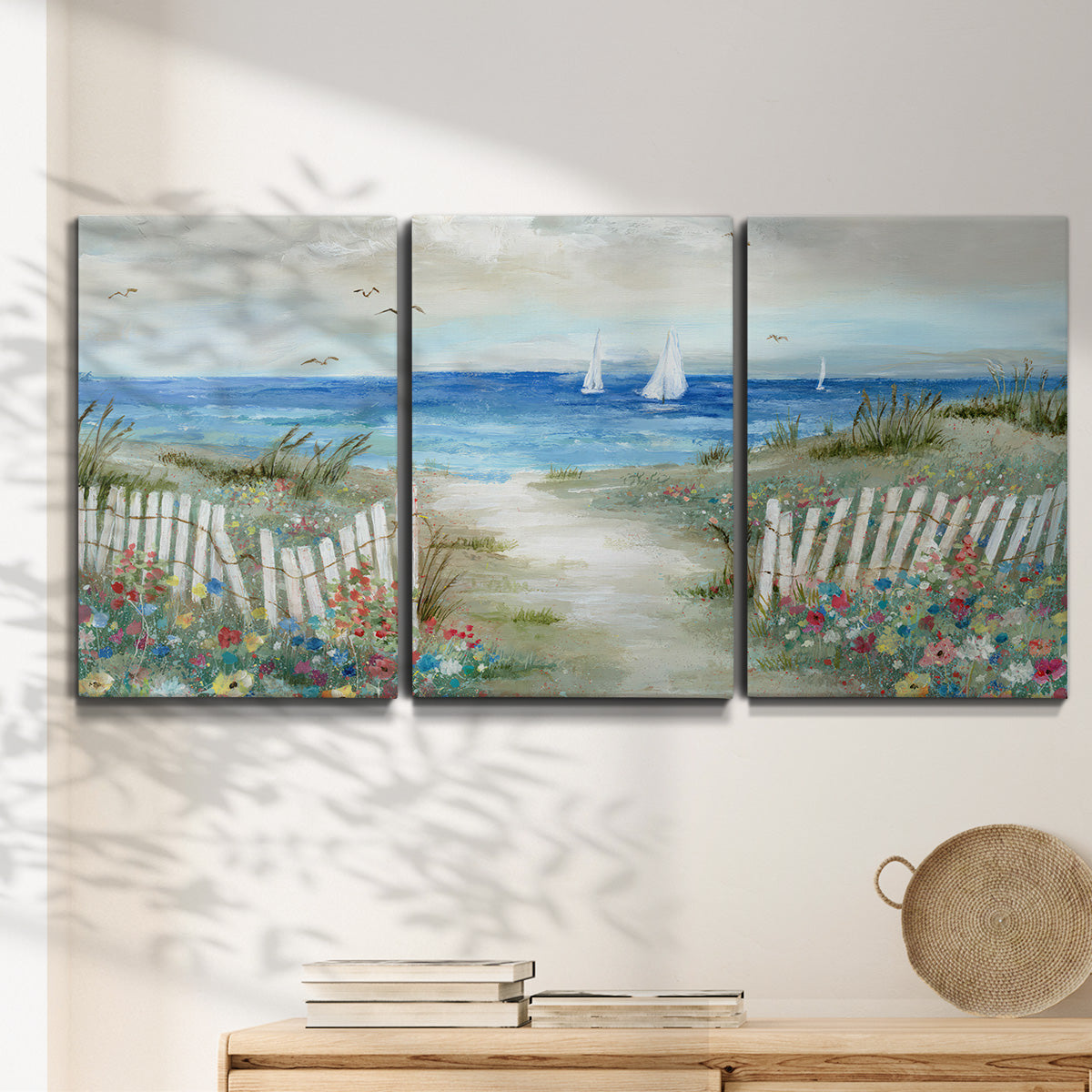 Three-panel canvas wall art featuring lush coastal garden landscape, displayed in a minimalist living room above a console table.