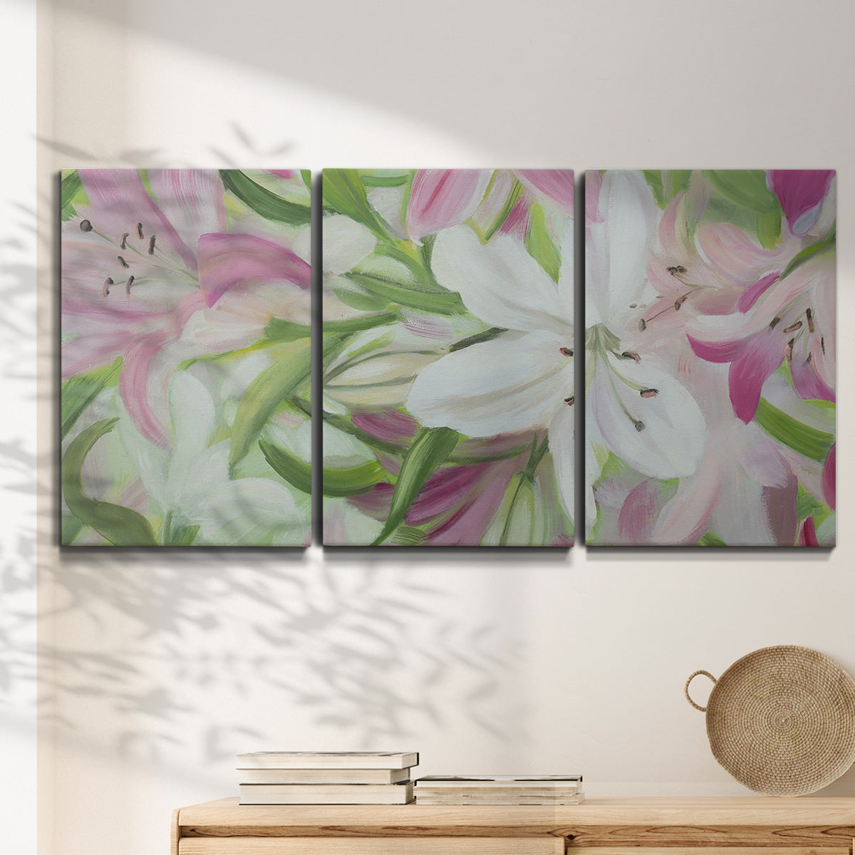 Three-panel canvas wall art featuring pink and white lilies botanical study, displayed in a minimalist living room above a console table.