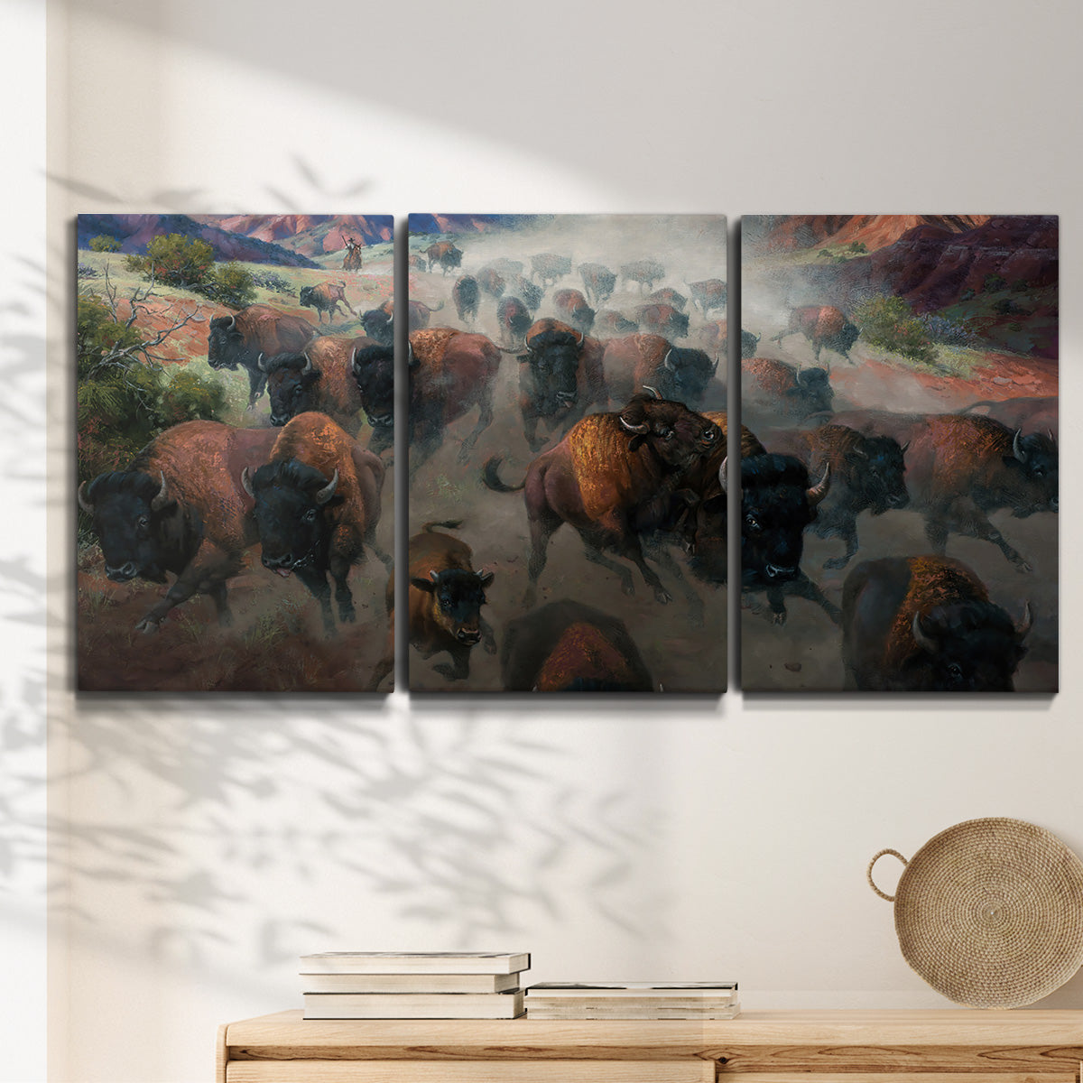 Three-panel canvas wall art featuring stormy canyon landscape with animals, displayed in a minimalist living room above a console table.