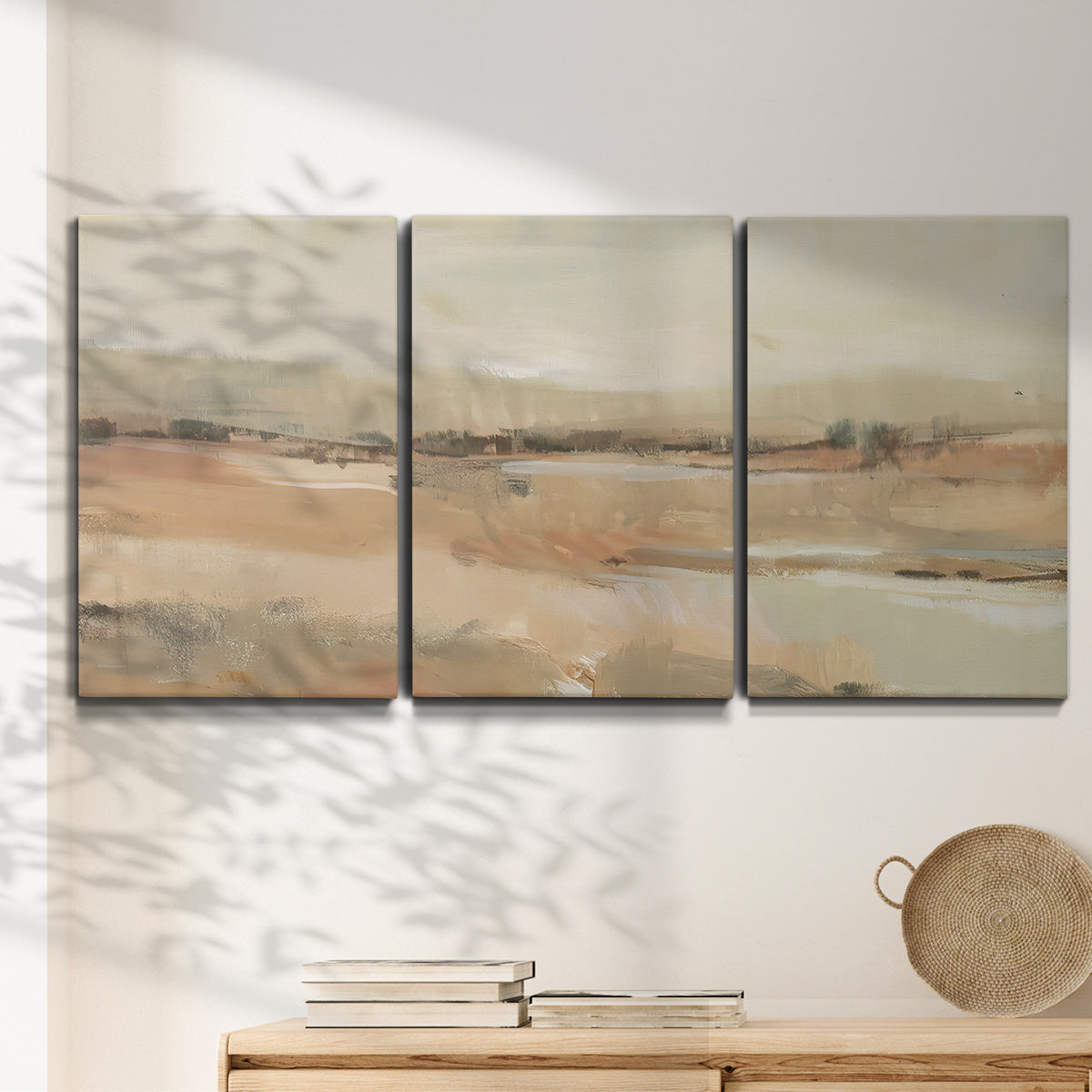 Three-panel canvas wall art featuring earth toned abstract landscape, displayed in a minimalist living room above a console table.