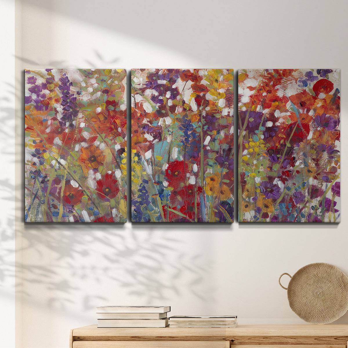 Three-panel canvas wall art featuring colorful floral arrangement, displayed in a minimalist living room above a console table.