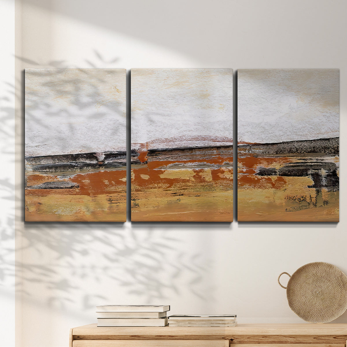 Three-panel canvas wall art featuring abstract bridge landscape in ochre, displayed in a minimalist living room above a console table.