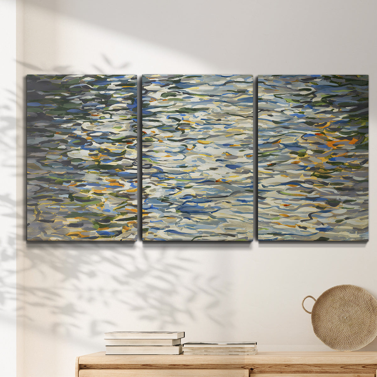 Three-panel canvas wall art featuring abstract water surface reflections, displayed in a minimalist living room above a console table.