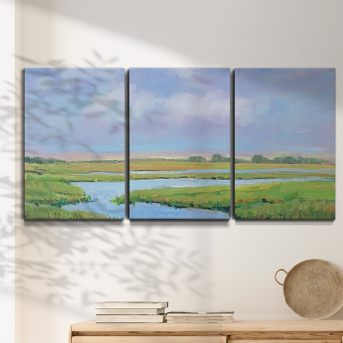 Three-panel canvas wall art featuring summer marshland with tall grasses, displayed in a minimalist living room above a console table.