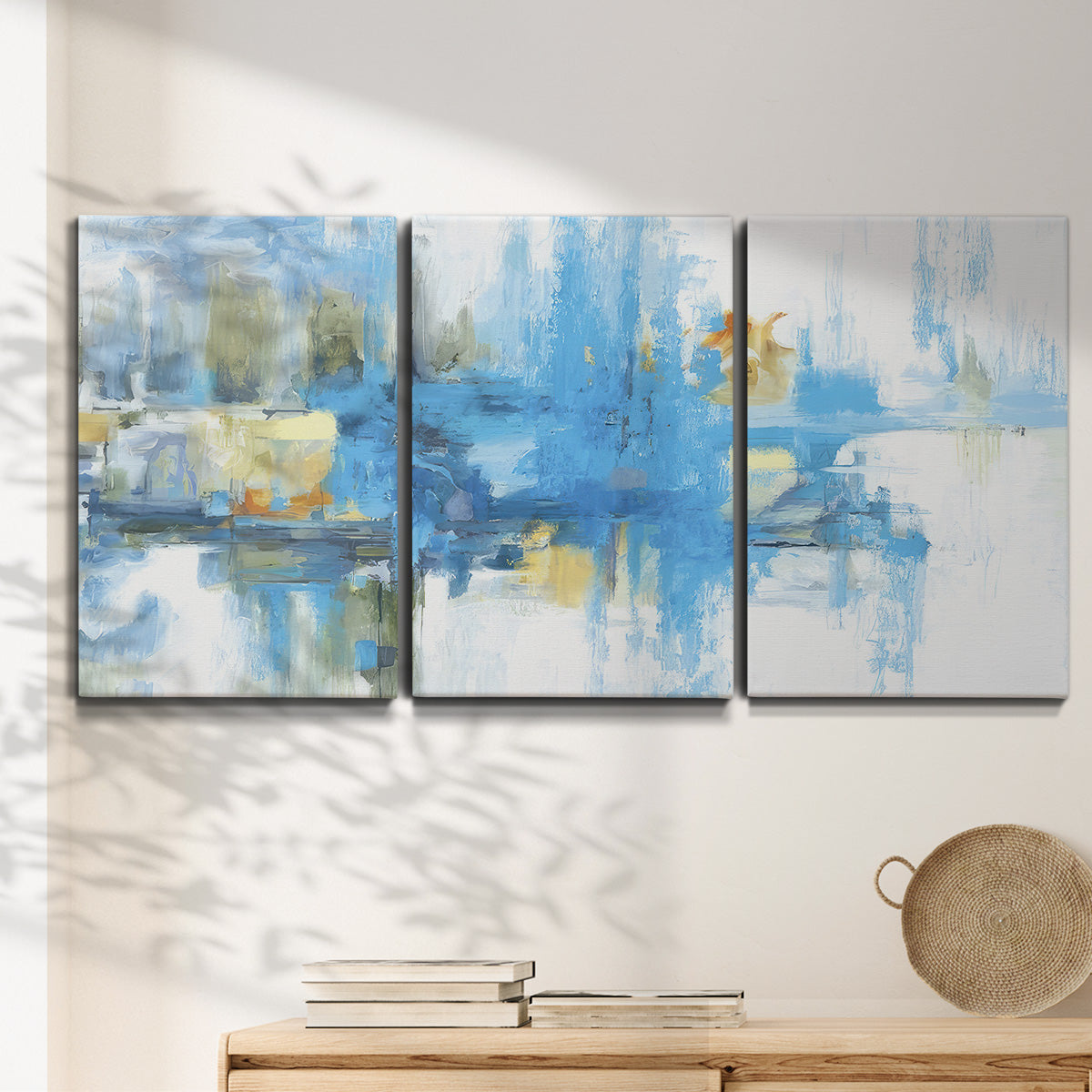 Three-panel canvas wall art featuring blue toned abstract city rhythm, displayed in a minimalist living room above a console table.