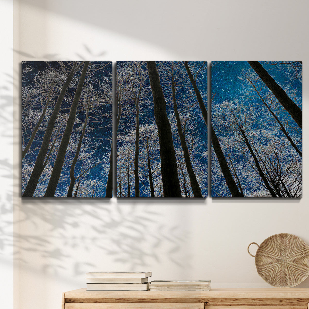 Three-panel canvas wall art featuring night landscape silhouette photography, displayed in a minimalist living room above a console table.