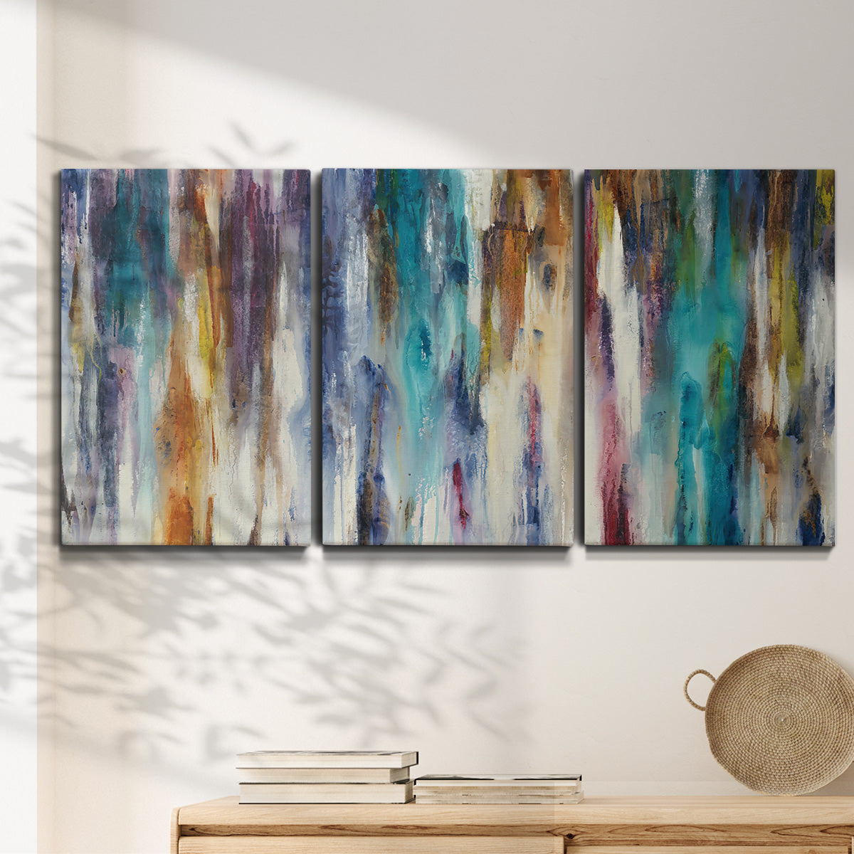 Three-panel canvas wall art featuring abstract shifting color forms, displayed in a minimalist living room above a console table.
