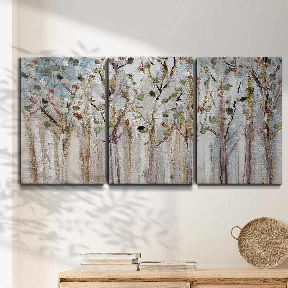 Three-panel canvas wall art featuring bare birch trees in winter forest, displayed in a minimalist living room above a console table.