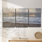 Three-panel canvas wall art featuring calm coastal shoreline seascape, displayed in a minimalist living room above a console table.