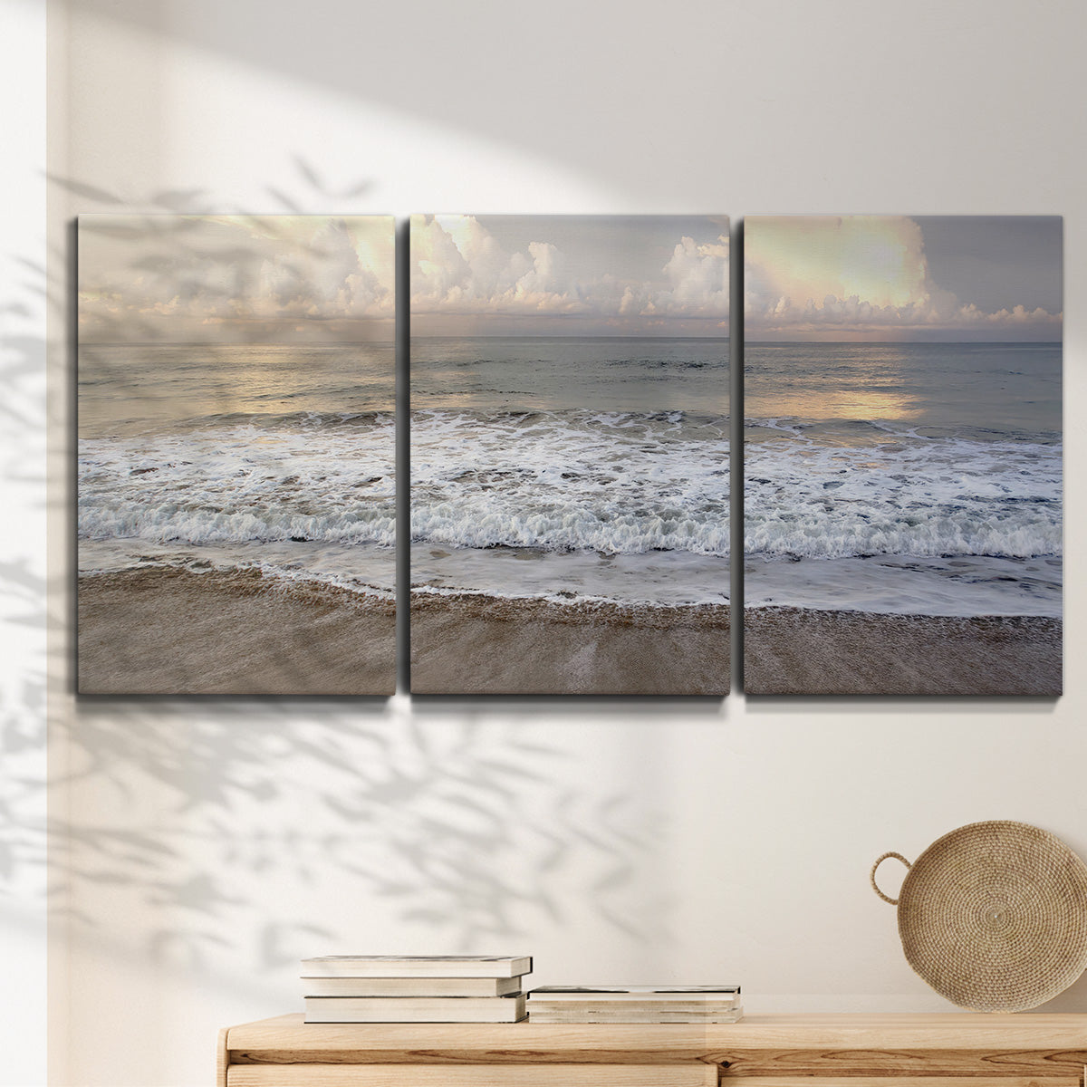 Three-panel canvas wall art featuring calm coastal shoreline seascape, displayed in a minimalist living room above a console table.