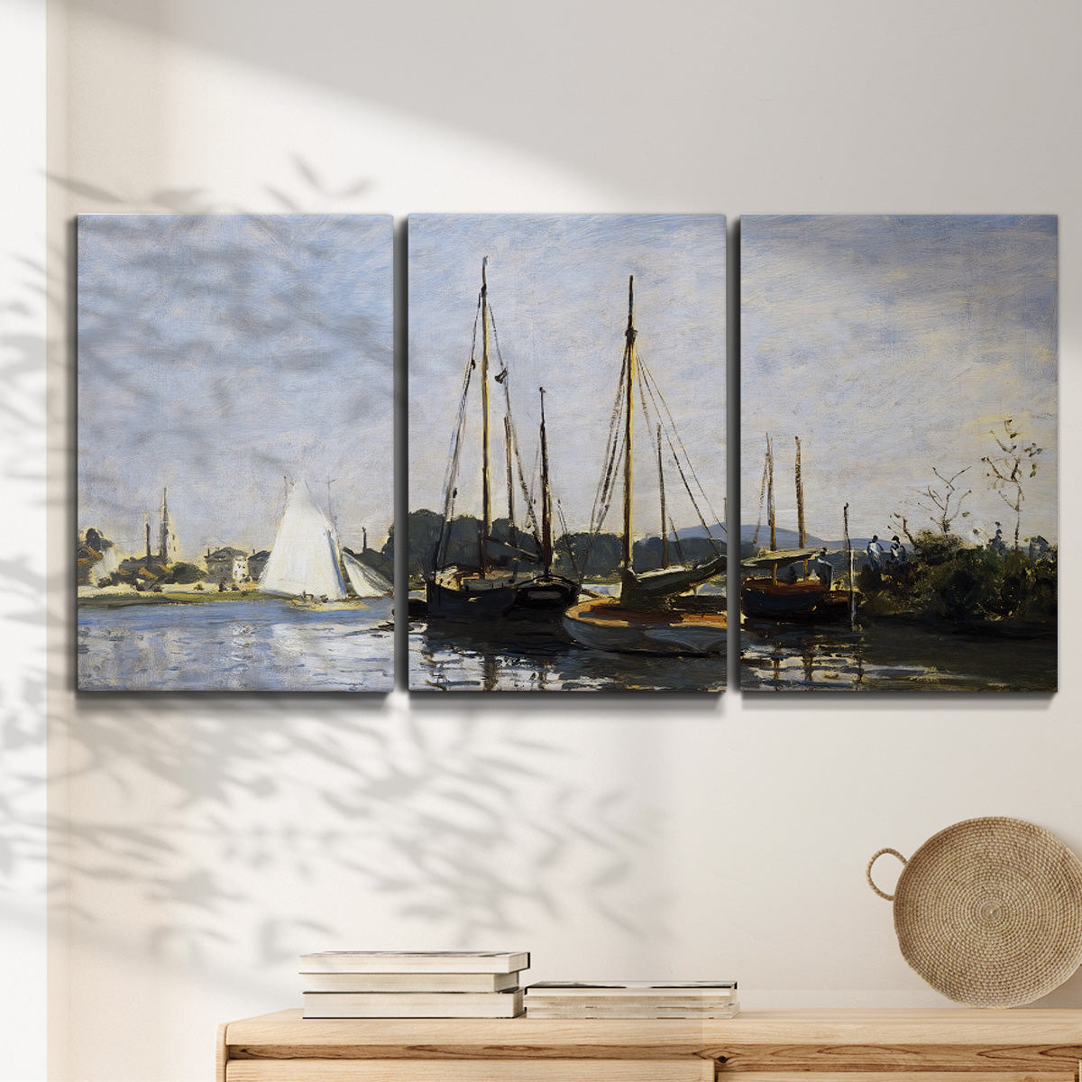 Three-panel canvas wall art featuring small pleasure boats on calm water, displayed in a minimalist living room above a console table.