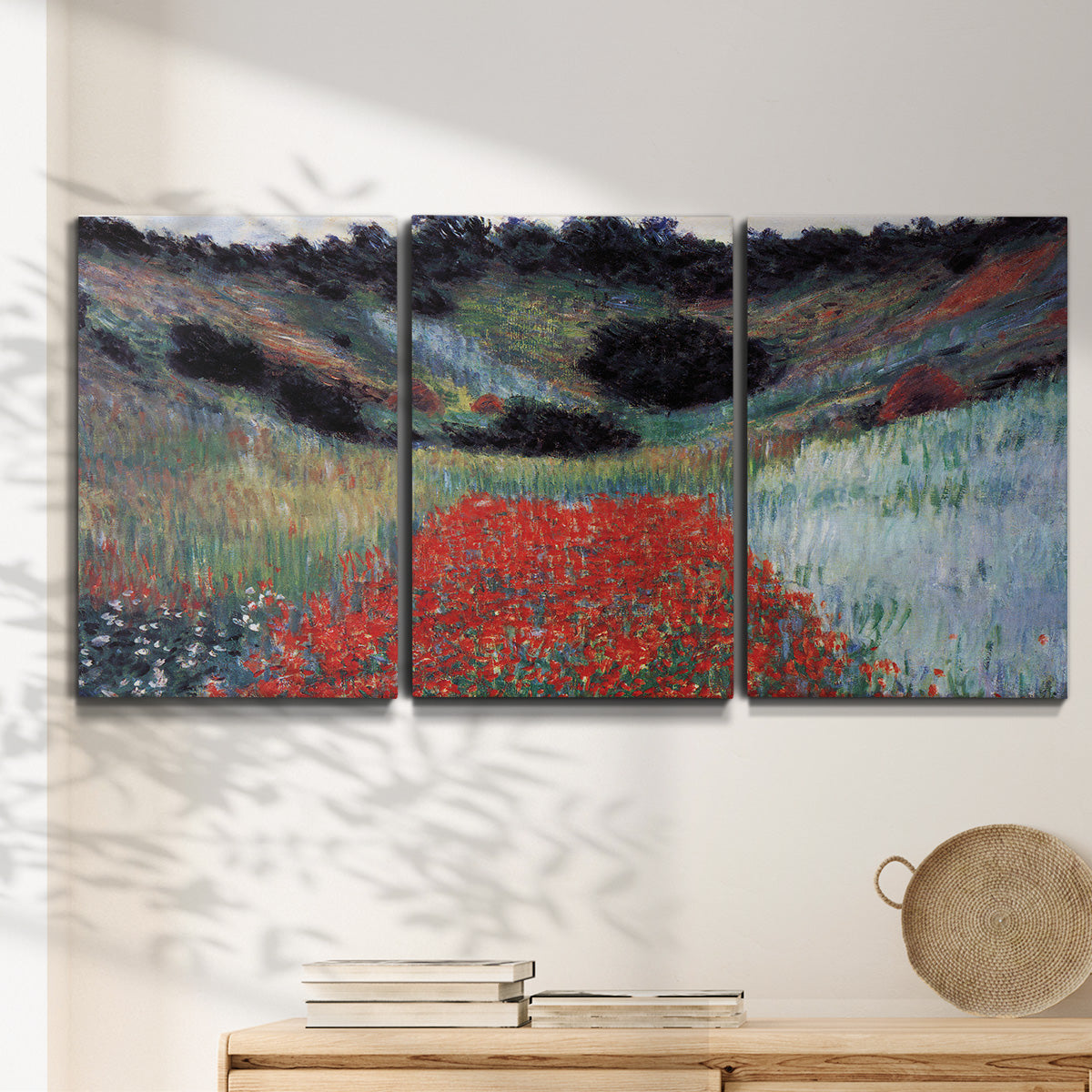 Three-panel canvas wall art featuring poppy field in shallow valley, displayed in a minimalist living room above a console table.