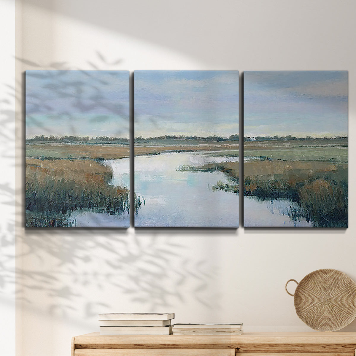 Three-panel canvas wall art featuring coastal plain with layered horizon, displayed in a minimalist living room above a console table.