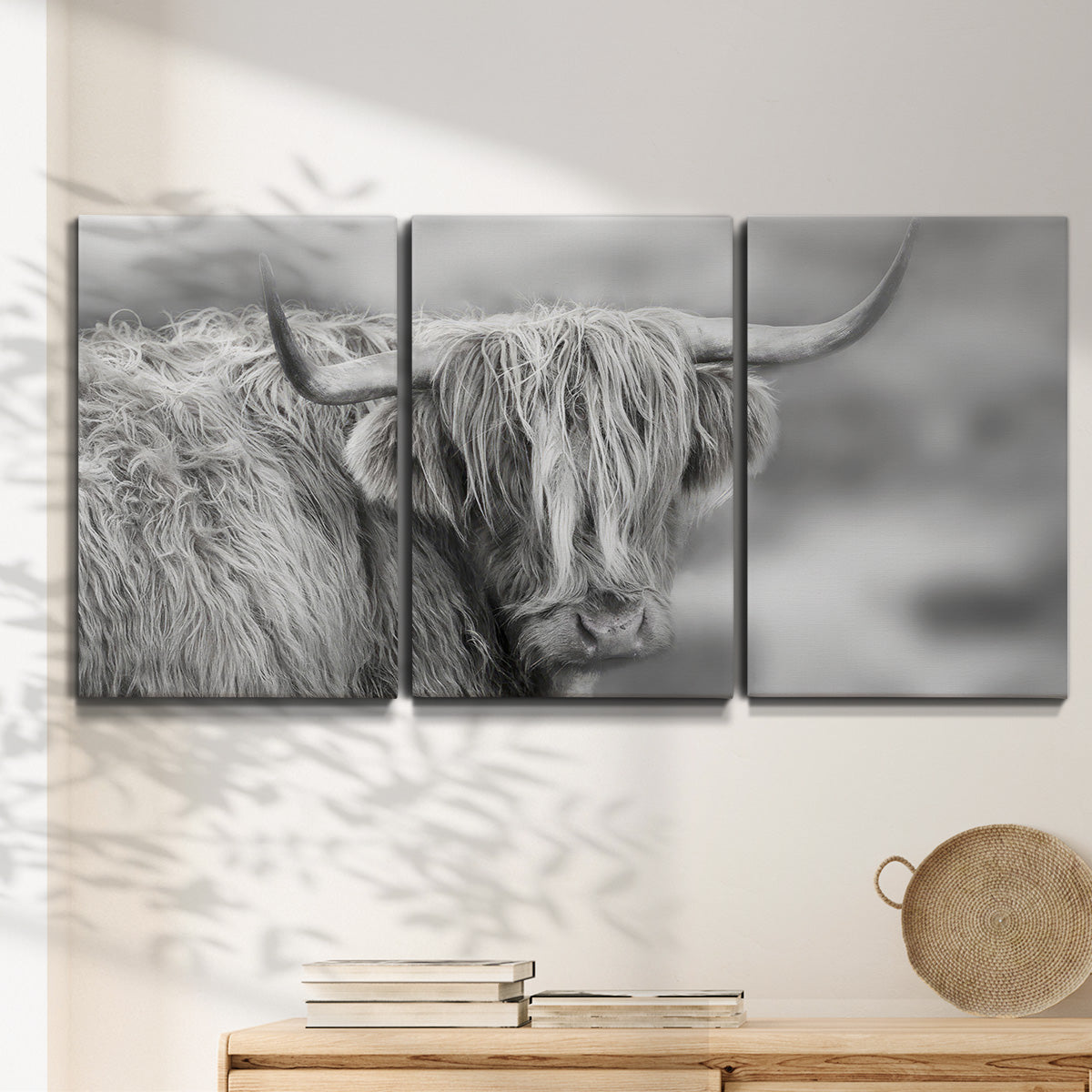 Three-panel canvas wall art featuring large highland cow portrait, displayed in a minimalist living room above a console table.