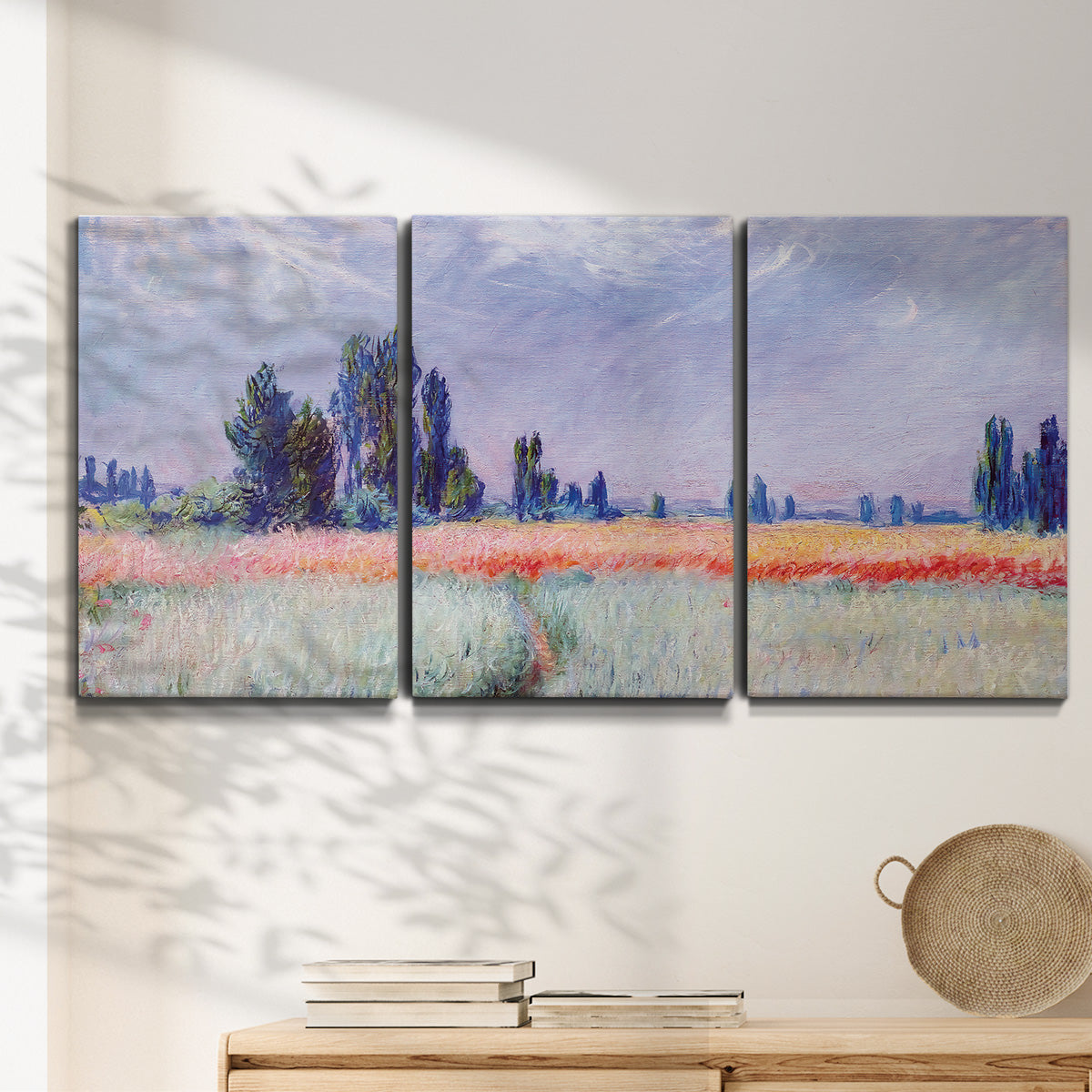 Three-panel canvas wall art featuring flowering field with poppies, displayed in a minimalist living room above a console table.