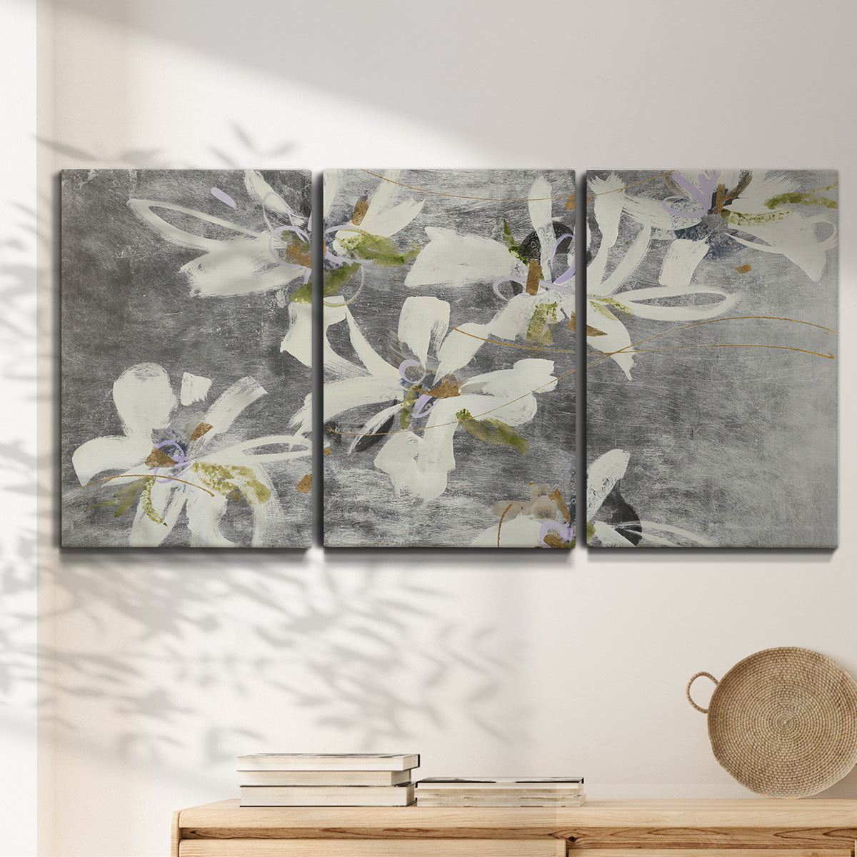 Three-panel canvas wall art featuring delicate floral symbolic arrangement, displayed in a minimalist living room above a console table.