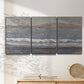 Three-panel canvas wall art featuring shoreline between land and sea, displayed in a minimalist living room above a console table.