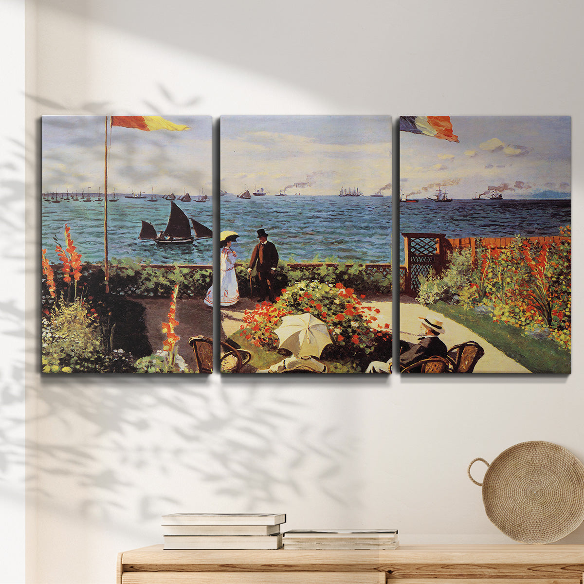 Three-panel canvas wall art featuring coastal garden overlooking sea, displayed in a minimalist living room above a console table.