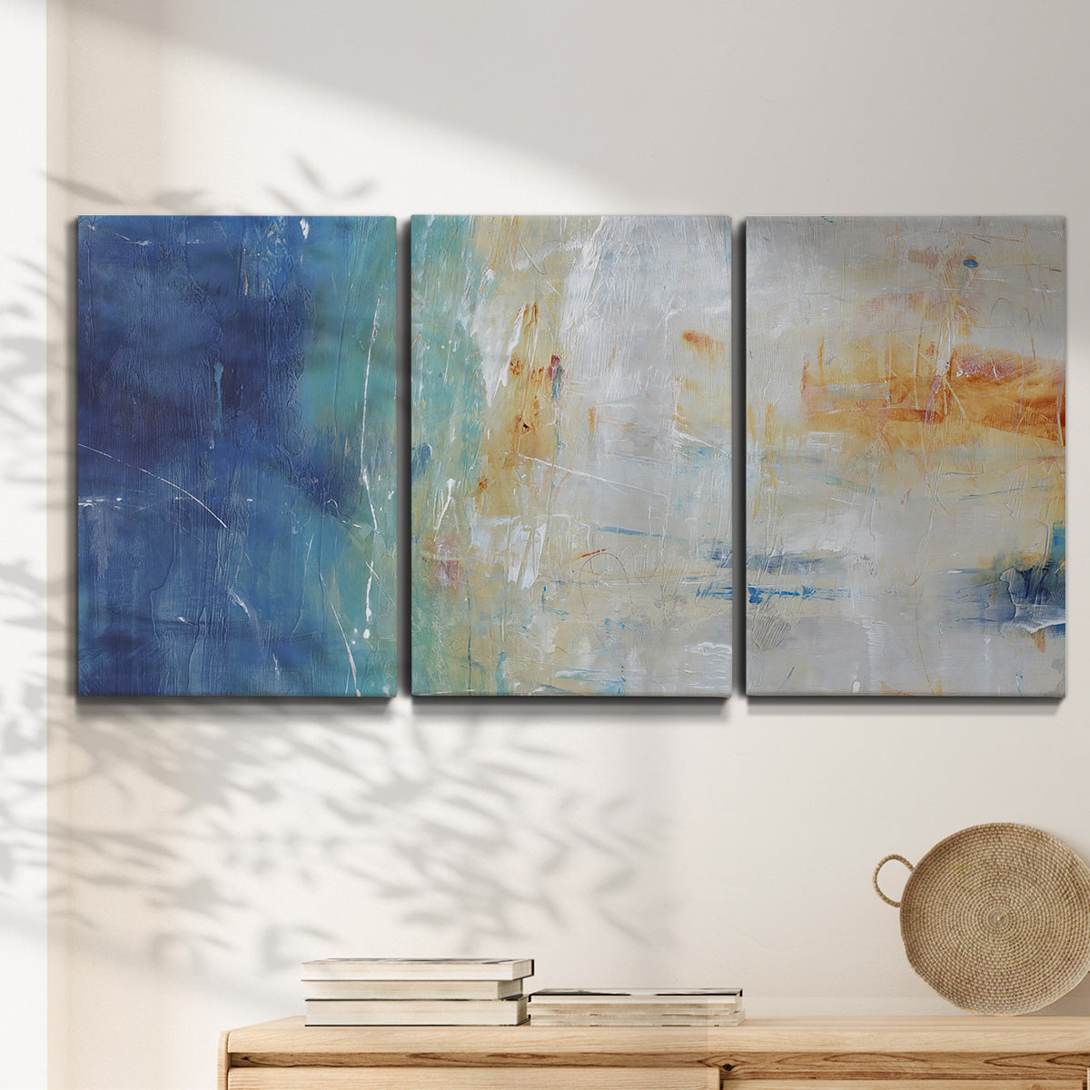 Three-panel canvas wall art featuring deep blue abstract grotto tones, displayed in a minimalist living room above a console table.