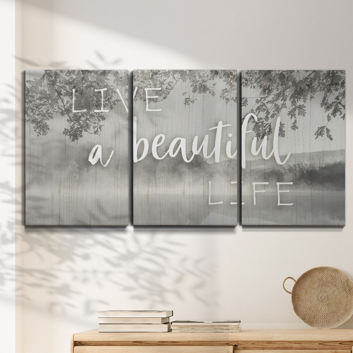 Three-panel canvas wall art featuring uplifting life themed typography, displayed in a minimalist living room above a console table.