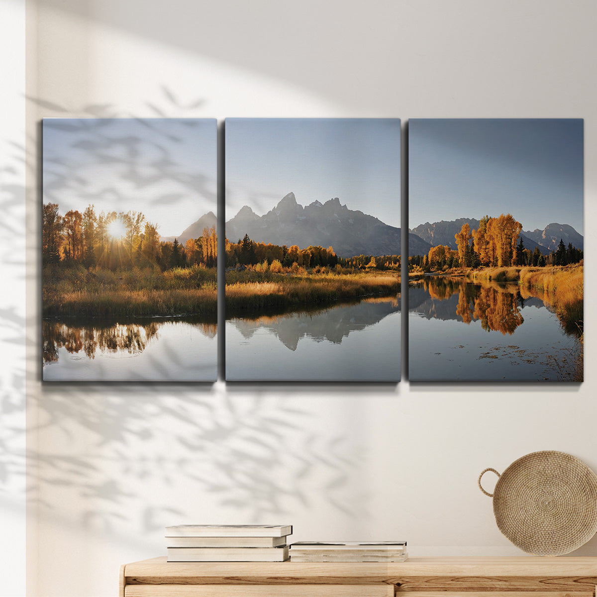 Three-panel canvas wall art featuring river canyon landscape photograph, displayed in a minimalist living room above a console table.