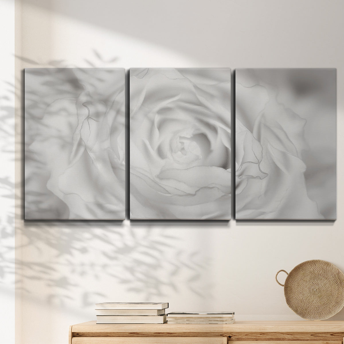 Three-panel canvas wall art featuring monochrome rose study photograph, displayed in a minimalist living room above a console table.
