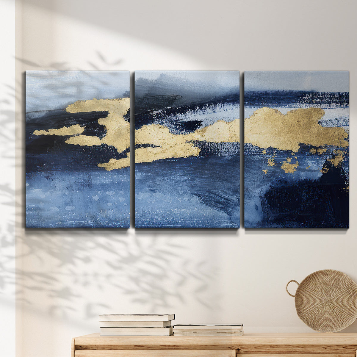 Three-panel canvas wall art featuring coastal shoreline with warm light, displayed in a minimalist living room above a console table.