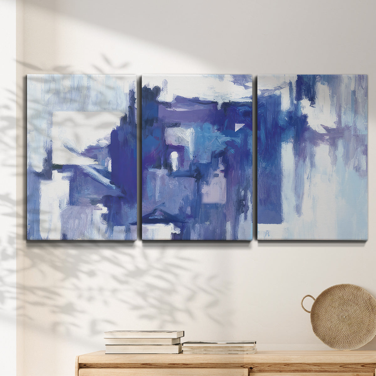 Three-panel canvas wall art featuring abstract urban street scene, displayed in a minimalist living room above a console table.