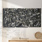 Three-panel canvas wall art featuring energetic expressionist abstract splatter, displayed in a minimalist living room above a console table.