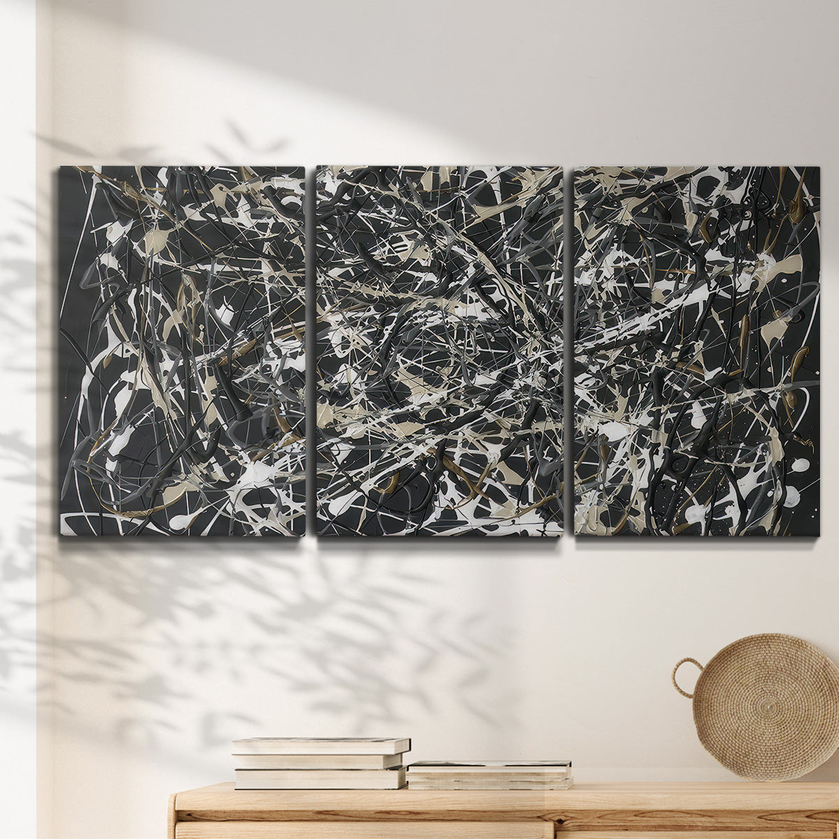 Three-panel canvas wall art featuring energetic expressionist abstract splatter, displayed in a minimalist living room above a console table.