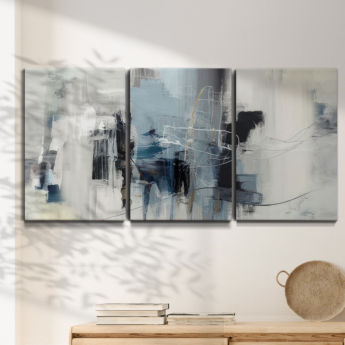 Three-panel canvas wall art featuring cool abstract winter color wash, displayed in a minimalist living room above a console table.