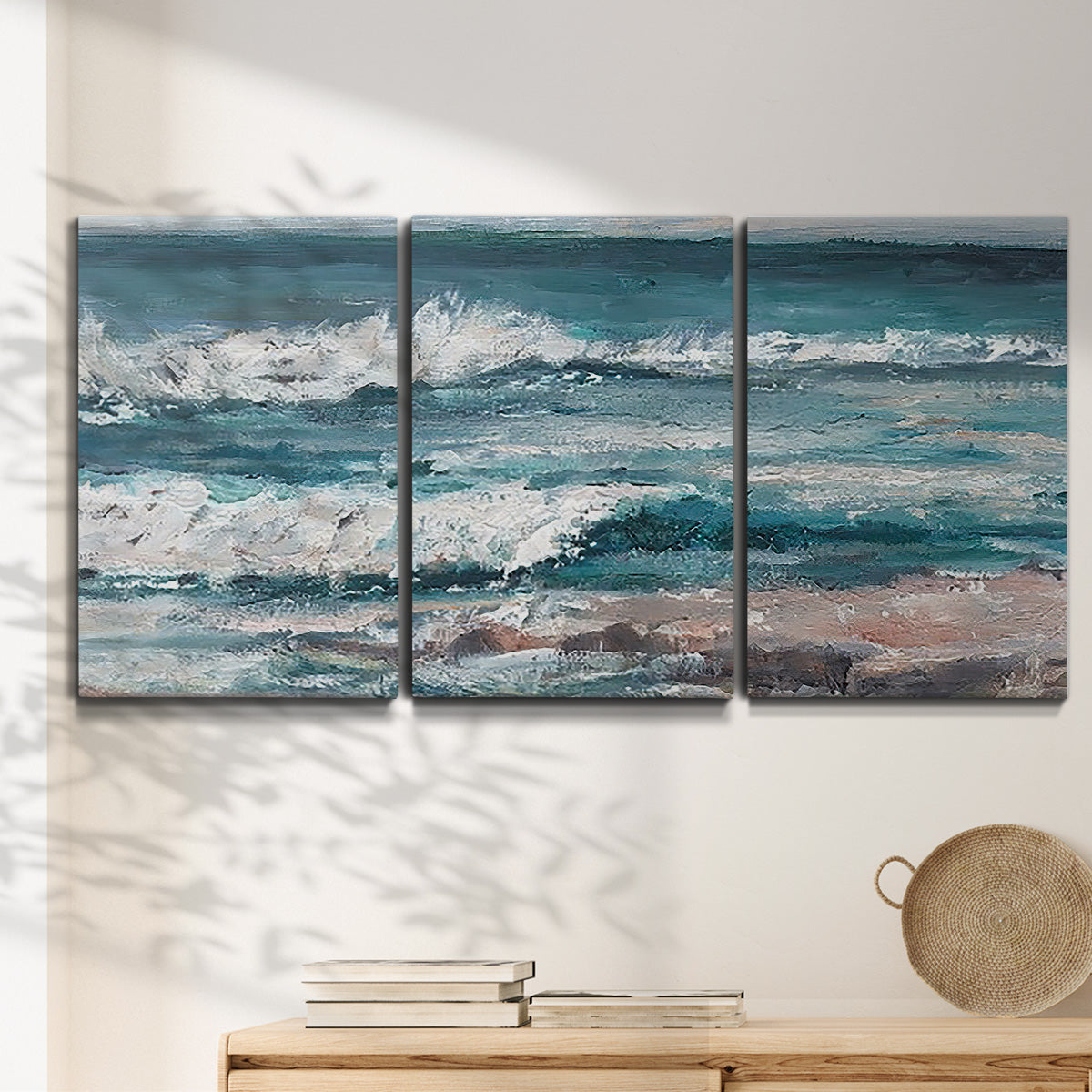 Three-panel canvas wall art featuring crashing ocean waves along shoreline, displayed in a minimalist living room above a console table.