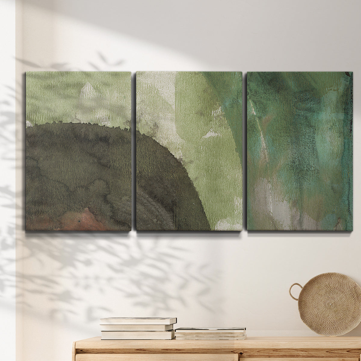 Three-panel canvas wall art featuring layered green abstract composition, displayed in a minimalist living room above a console table.