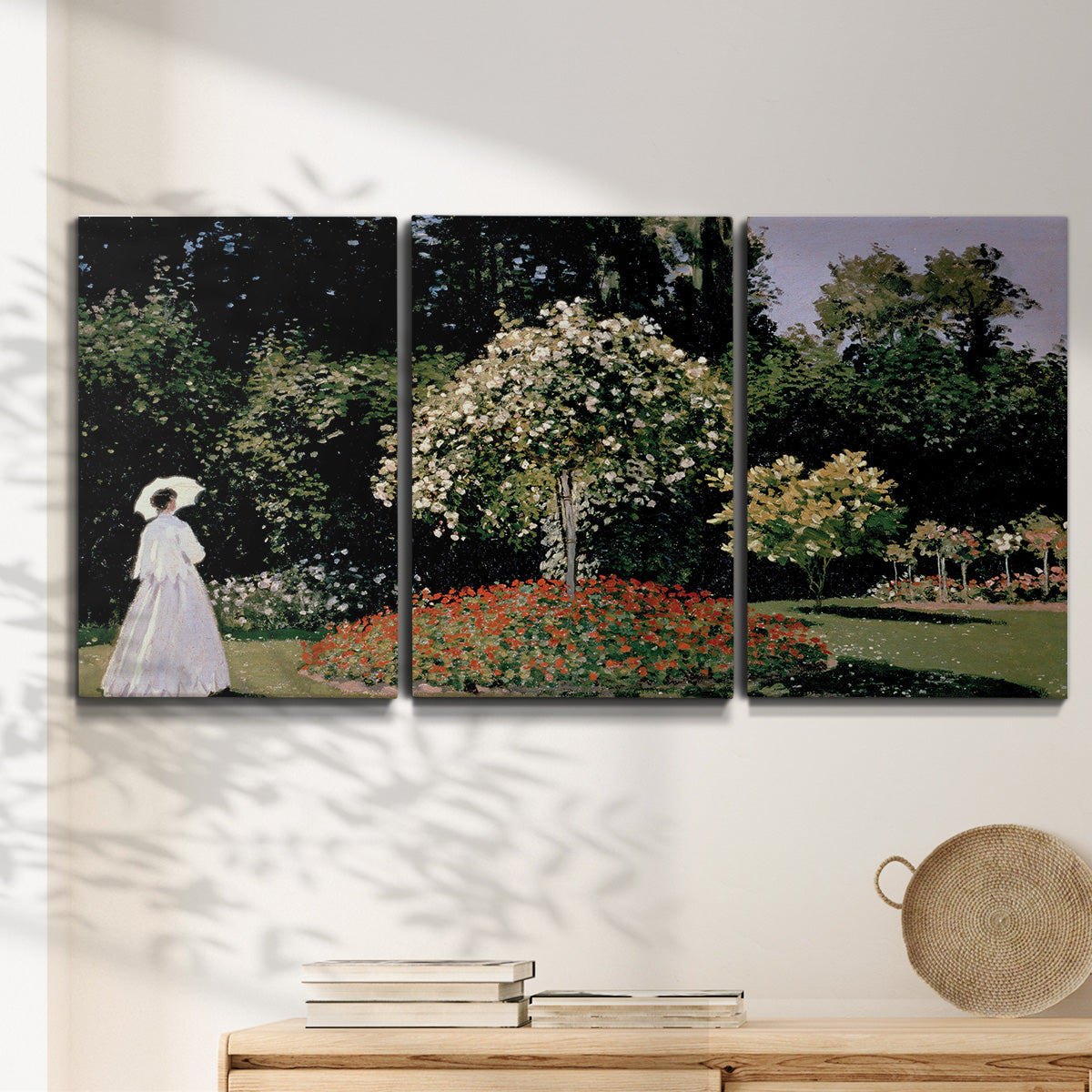 Three-panel canvas wall art featuring woman seated in garden landscape, displayed in a minimalist living room above a console table.