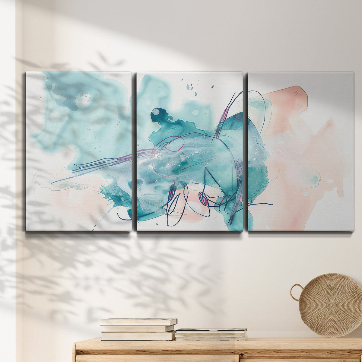 Three-panel canvas wall art featuring soft abstract watercolor forms, displayed in a minimalist living room above a console table.