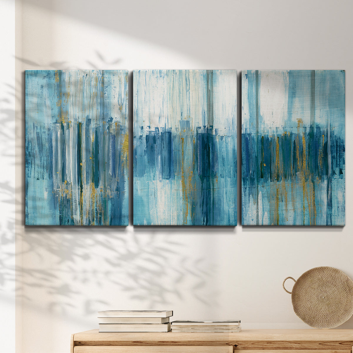 Three-panel canvas wall art featuring layered abstract earth tones, displayed in a minimalist living room above a console table.
