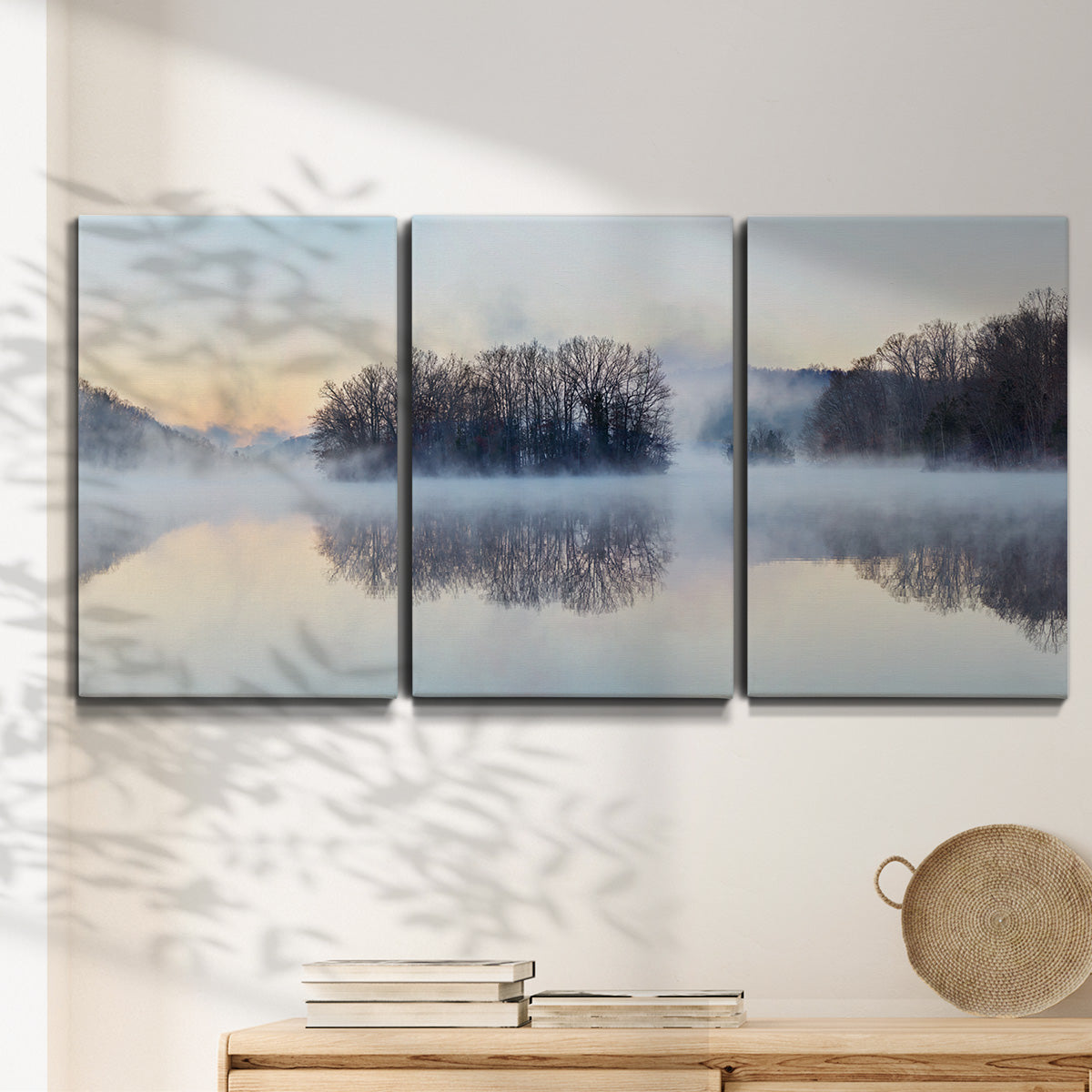 Three-panel canvas wall art featuring misty water landscape photograph, displayed in a minimalist living room above a console table.