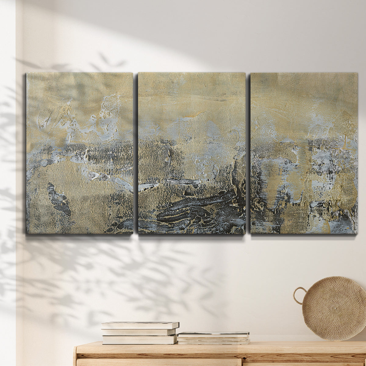 Three-panel canvas wall art featuring gold toned abstract horizon, displayed in a minimalist living room above a console table.